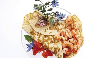 Crepe filled with crayfish and clover, garnished with clover blossoms and diced red peppers