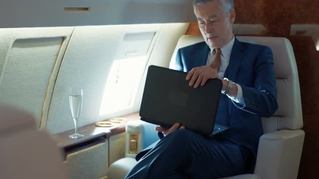  Successful businessman working on laptop while traveling by private plane