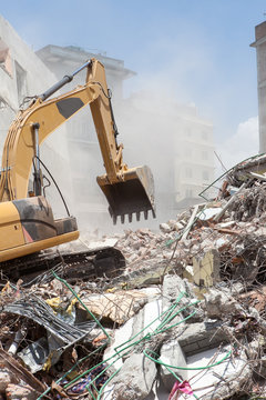 An excavator clearing off debris of a fallen building.