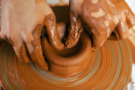 Hands of a ceramist working on a potter's wheel.
