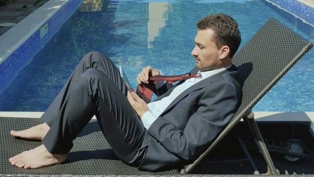 Businessman works with tablet near the swimming pool