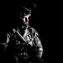 Naklejka premium Studio contour backlight shot of special forces soldier in uniforms with weapons, portrait on black background