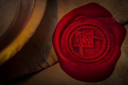 Freemason secret symbol concept with vintage letter under a candle, sealed with red wax seal with the square, the compass and the G letter in the middle, one of the most identifiable masonic symbols