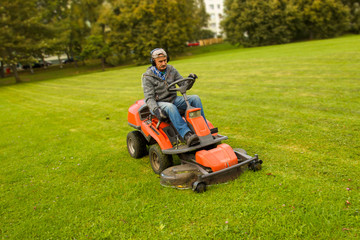a man driving a lawn mower in a city park
