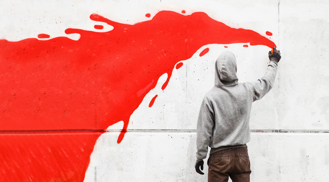 Street artist drawing with spraycan on wall