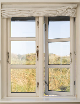 Open wooden window with a view of the dunes in Denmark