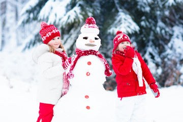 Kids building snowman. Children in snow. Winter fun.