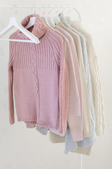 Warm pastel sweaters on hangers