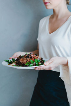 Woman holding a dish of Coq au vin