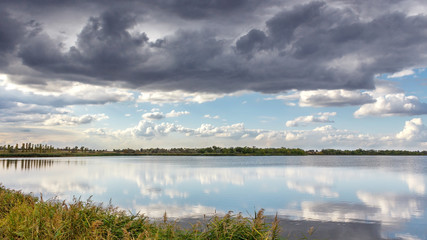 Cyclist riding a bicycle on the Sava river bank, with some dramatic sky at spring time