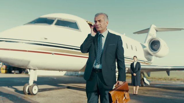  Middle Eastern businessman talking on phone before boarding private jet