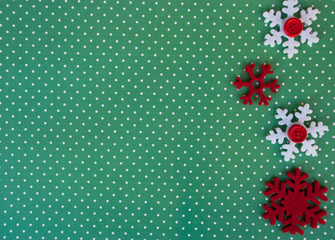Fototapeta na wymiar New year background with red snowflakes on green paper with white points. Christmas card idea.Space for text.Xmas blank.