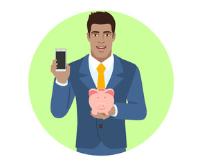Businessman holding mobile phone and piggy bank