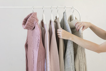 Choosing warm pastel sweaters on hangers