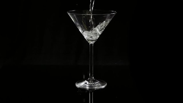 Pouring white martini in a cocktail glass - a classic drink