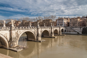 st angelo bridge in Rome on a sunny cloudy day with murky waters of Tiber river