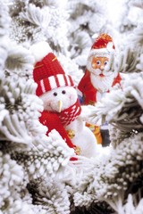 Snowman figure and a chocolate Santa Claus in a snowy forest