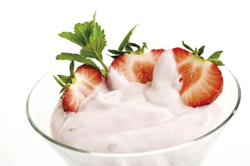 Glass of yogurt garnished with strawberries and mint leaves
