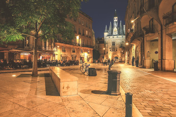 View of historical Porte Cailhau at night with full of people having dinner on restaurant terrace in Bordeaux, Gironde, Aquitaine, France - obrazy, fototapety, plakaty