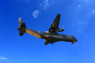 Samolot wojskowy, transportowy na tle błękitnego nieba i księżyca.