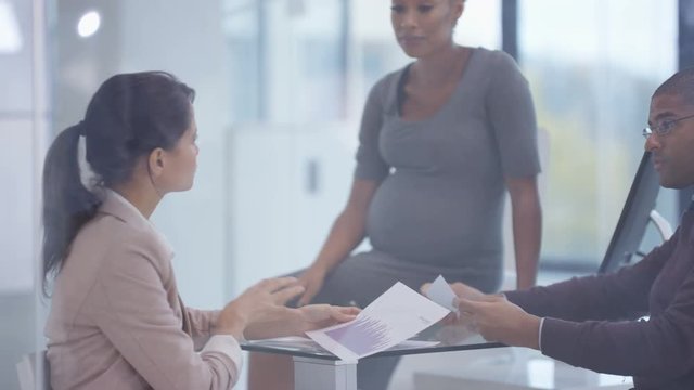  Business team including pregnant woman discussing paperwork in a meeting
