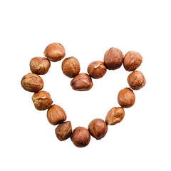 Raw hazelnuts in heart shape isolated on white background, top view