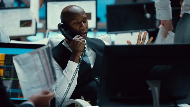  Financial trader in busy trading room negotiating a difficult deal over phone