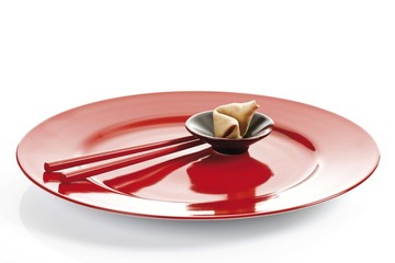 Fortune cookies with chopsticks on a red plate