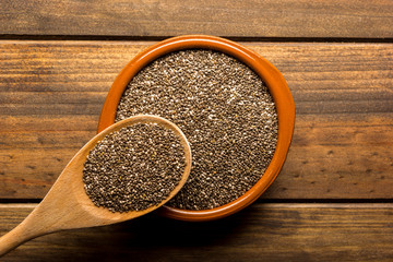 Group of chia seeds in a bowl on a wooden table.