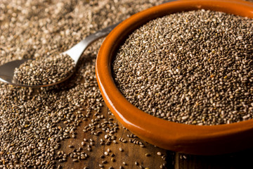 Group of chia seeds in a bowl on a wooden table.
