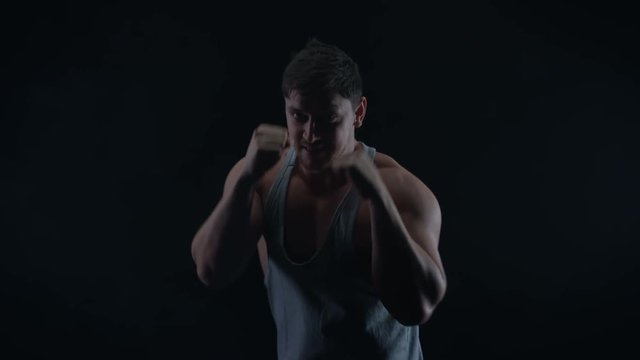  Muscular boxer training, throwing punches towards camera with bare fists.