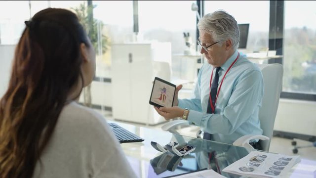  Audiology doctor with patient, showing her diagram of inner ear