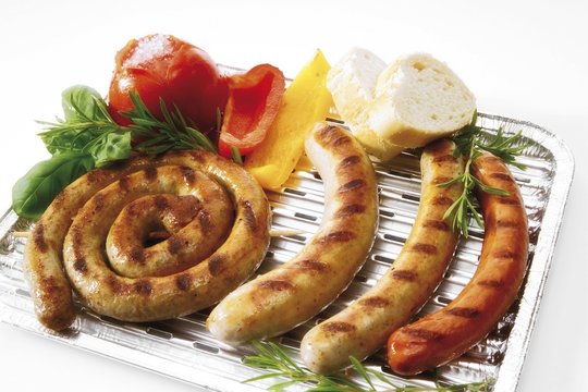 Aluminium barbecue tray with bratwurst, bratwurst snail, beef bratwurst, grilled tomato, capsicum, herbs and white bread