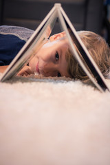 Cute boy peeking through a book.