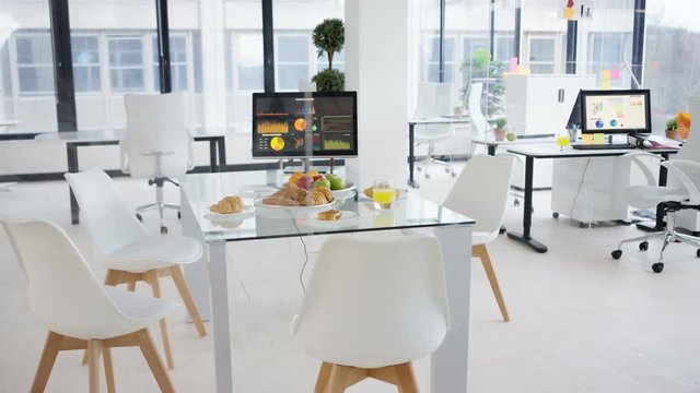  Interior empty office, desk laid with fruit & pastries for morning meeting