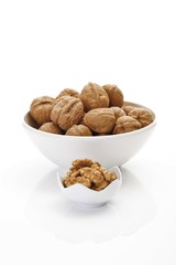 Un-shelled walnuts and shelled walnut kernels in porcelain bowls