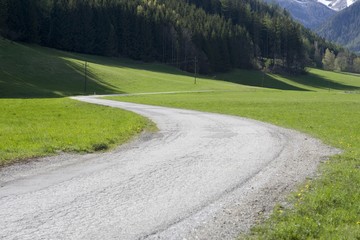 S-shaped road along a meadow and between mountains