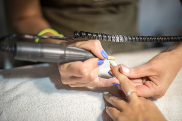 Obraz premium Hardware manicure. Removal of old gel varnish in the salon. Manicure master doing beauty procedure for client, closeup and top view