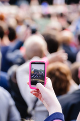 Many people at an outdoor concert using mobile phones to take photographs or videos