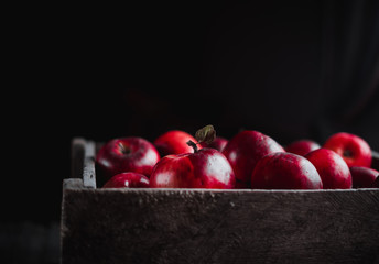 box with red apples on black background.