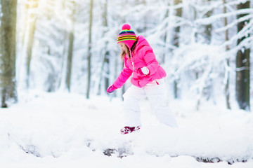 Child playing with snow in winter. Kids outdoors.