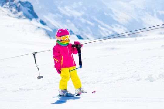 Child on ski lift in snow sport school in winter mountains