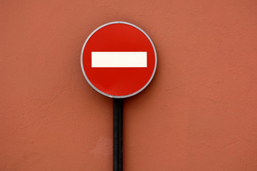 Traffic sign No Entry in front of red wall