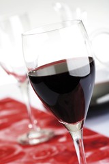 Red wine glasses on table runner with wine decanter in background