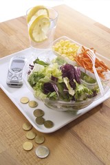 Lunch to go: colourful salad with corn and carrots on a tray with mobile phone and change