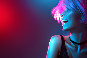 Beauty model girl in colorful bright lights with trendy makeup and haircut - obrazy, fototapety, plakaty
