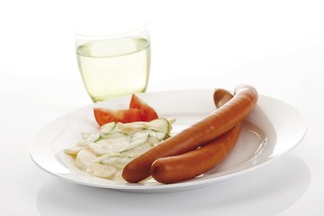 Sausages with potato salad on a plate and a glass of mineral water