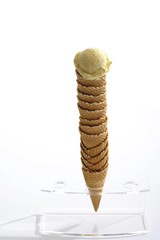 Stack of ice-cream cones placed in a stand and topped with a scoop of ice-cream