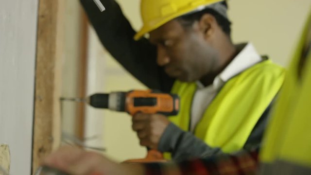  Construction workers on a building site drilling & checking wiring