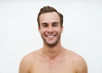 Close up headshot young caucasian  guy in smile opposite white wall